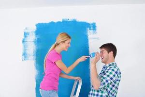 pareja feliz pintando una pared en su nuevo hogar foto