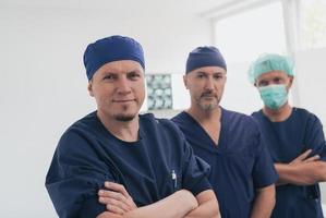 Multiethnic orthopedic doctor in front of his medical team looking at camera wearing face mask photo