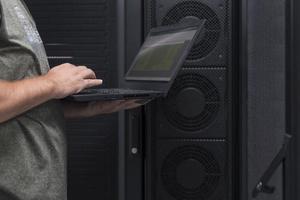Data Center Engineer Using Laptop Computer. Server Room Specialist Facility with Korean Male System Administrator Working with Data Protection Network for Cyber Security. photo