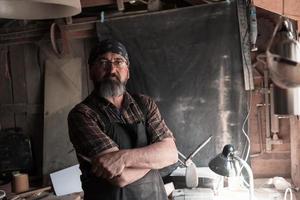 Spoon craft master in his workshop with handmade wooden products and tools photo