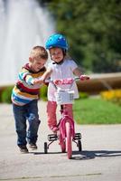 Boy and girl in park learning to ride a bike photo