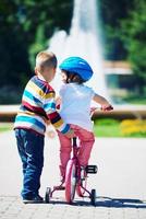 Boy and girl in park learning to ride a bike photo