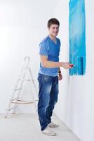 handsome young man paint white wall in color photo