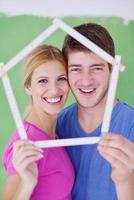 pareja feliz pintando una pared en su nuevo hogar foto