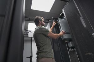 IT engineer working In the server room or data center The technician puts in a rack a new server of corporate business mainframe supercomputer or cryptocurrency mining farm. photo