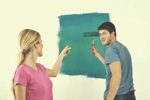 pareja feliz pintando una pared en su nuevo hogar foto