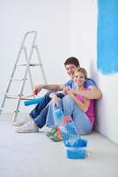 pareja joven feliz relajándose después de pintar en un nuevo hogar foto