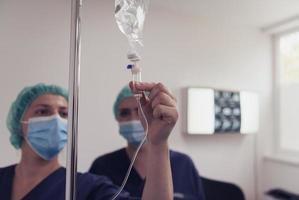 General practitioner holding intravenous drip infusion. Doctor handling IV fluid drip with copy space on white background. Nurse performing Intravenous therapy. photo