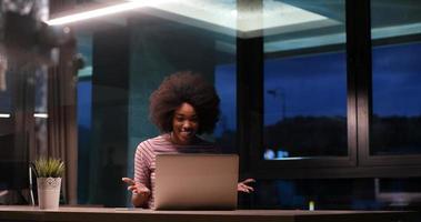 black businesswoman using a laptop in night startup office photo