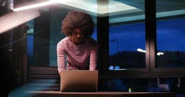 black businesswoman using a laptop in night startup office photo