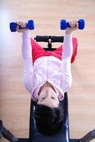 .una mujer joven levantando pesas en el gimnasio foto