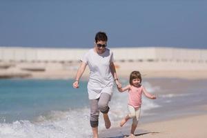 mother and daughter running on the beach photo