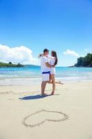 pareja romántica enamorada diviértete en la playa con el corazón dibujando en la arena foto