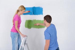 pareja feliz pintando una pared en su nuevo hogar foto