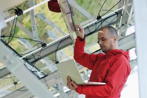 engineer using laptop at solar panels plant field photo