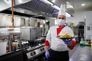 chef cook wearing face protective medical mask for protection from coronavirus photo