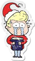 distressed sticker cartoon of a crying man holding book wearing santa hat vector