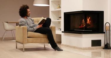 young man at home reading book photo