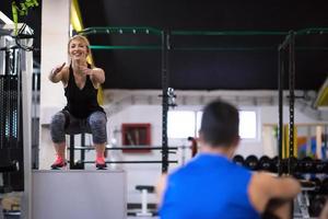 mujer haciendo ejercicio con entrenador personal saltando en la caja de ajuste foto