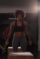 black female athlete is performing box jumps at gym photo
