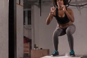 atleta femenina negra está realizando saltos de caja en el gimnasio foto