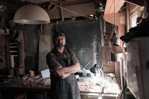 maestro de artesanía de cucharas en su taller con productos y herramientas de madera hechos a mano foto