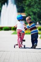 Boy and girl in park learning to ride a bike photo