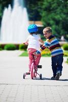 niño y niña en el parque aprendiendo a andar en bicicleta foto