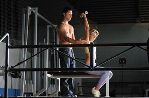 mujer joven en gimnasio con entrenador foto