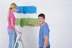 pareja feliz pintando una pared en su nuevo hogar foto