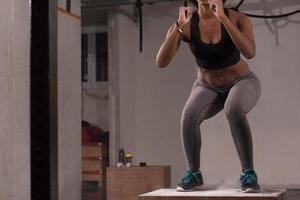 black woman is performing box jumps at gym photo