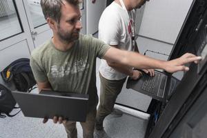 Technicians team updating hardware inspecting system performance in super computer server room or cryptocurrency mining farm. photo