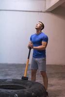 man workout with hammer and tractor tire photo