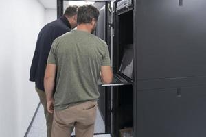 Technicians team updating hardware inspecting system performance in super computer server room or cryptocurrency mining farm. photo