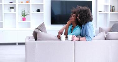 multiethnic couple sitting on sofa at home drinking coffe photo