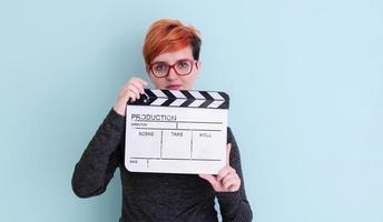 redhead woman holding movie  clapper on cyan background photo