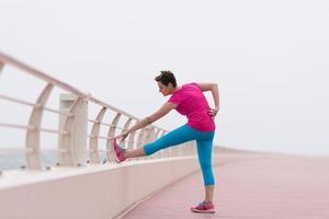 mujer estirándose y calentándose en el paseo marítimo foto