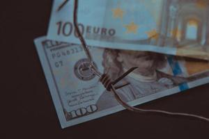 conflictos euro-dólar, billete dólar y billete euro, euro vs dólar con alambre de púas, crisis económica foto