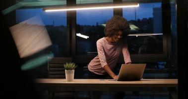 mujer de negocios negra que usa una computadora portátil en la oficina de inicio nocturno foto