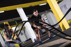 sports couple doing battle ropes cross fitness exercise photo