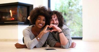 multiethnic couple showing a heart with their hands on the floor photo