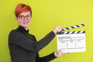 redhead woman holding movie  clapper on green background photo