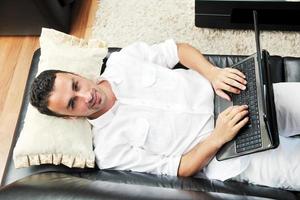 Portrait of a relaxed young guy using laptop at home photo