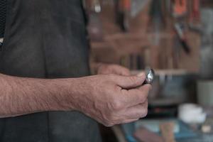 Manos tallando cuchara de madera, trabajando con cincel de cerca. taller de madera. proceso de elaboración de una cuchara de madera foto