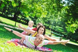 Feliz pareja joven con sus hijos divertirse en el parque foto