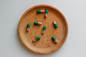 Intestinal-soluble capsules with vitamins on a wooden plate. Health care, medicine photo