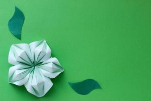 banner con flor de origami verde y hojas de papel con lugar para su diseño. fondo de papel foto