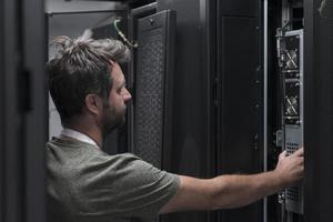 IT engineer working In the server room or data center The technician puts in a rack a new server of corporate business mainframe supercomputer or cryptocurrency mining farm. photo
