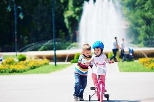 Boy and girl in park learning to ride a bike photo