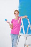 happy smiling woman painting interior of house photo